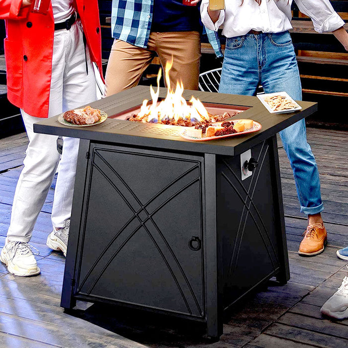 Friends gathered around the square propane fire pit table on a deck