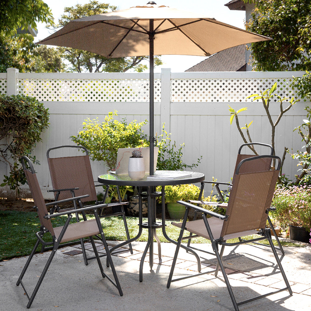 Tan patio dining set with umbrella by a white fence