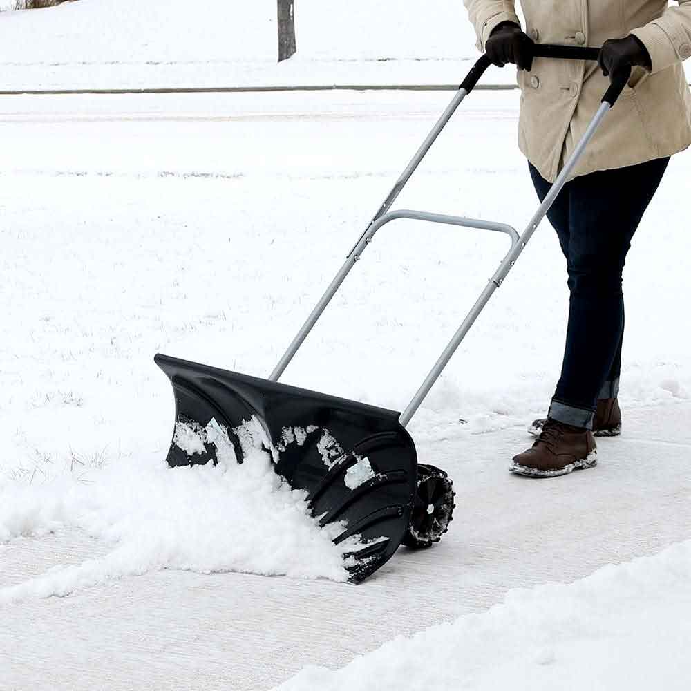 Man pushing snow along a path with the rolling snow pusher