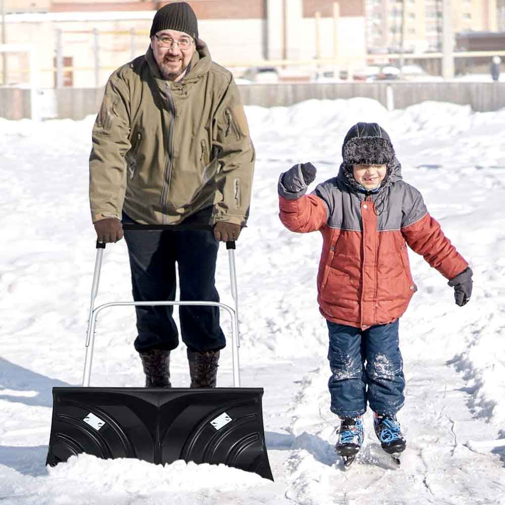 Father and child in the snow with the rolling snow pusher