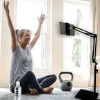Woman following a home workout on a tablet held by the black stand