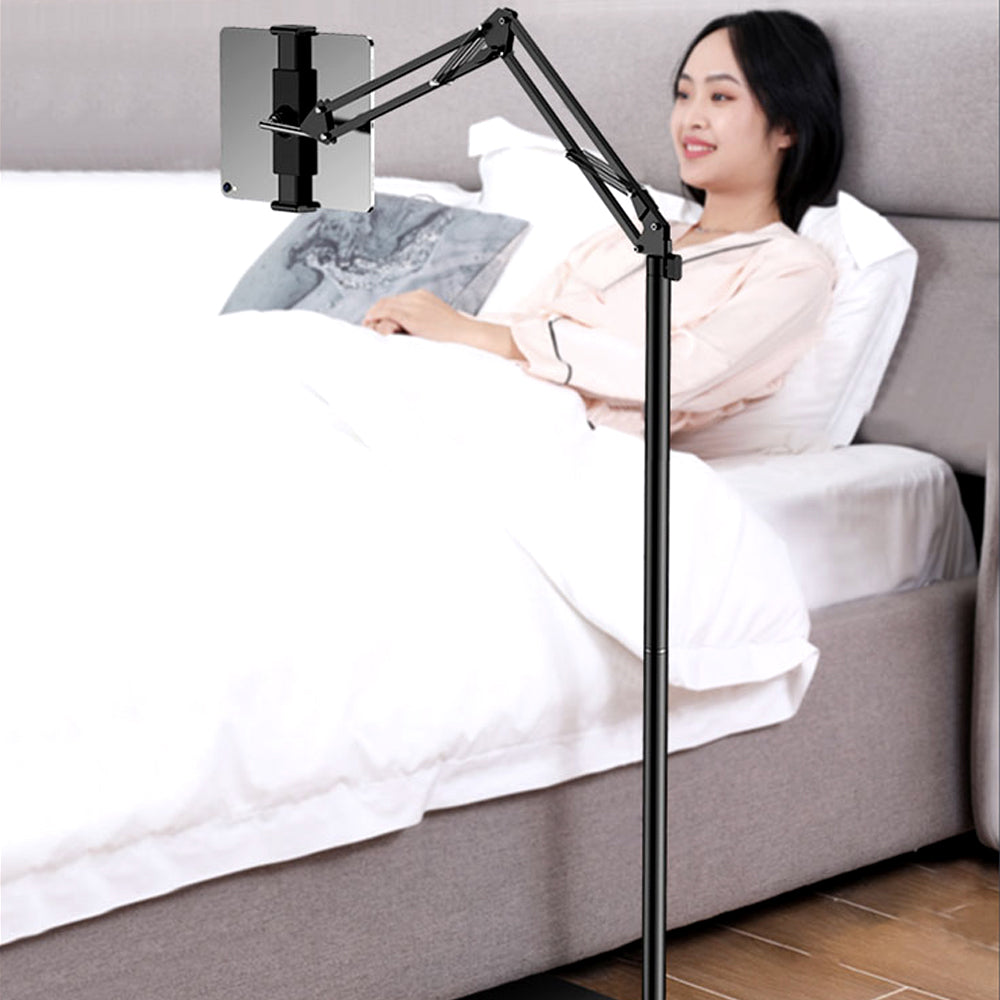 Woman reading in bed with a tablet on the floor stand