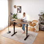 Woman standing at a wood-top standing desk in a bright room