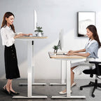 Two women at standing desks, one standing and one seated