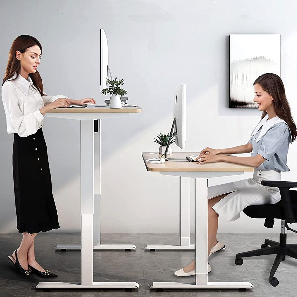 Two women at standing desks, one standing and one seated