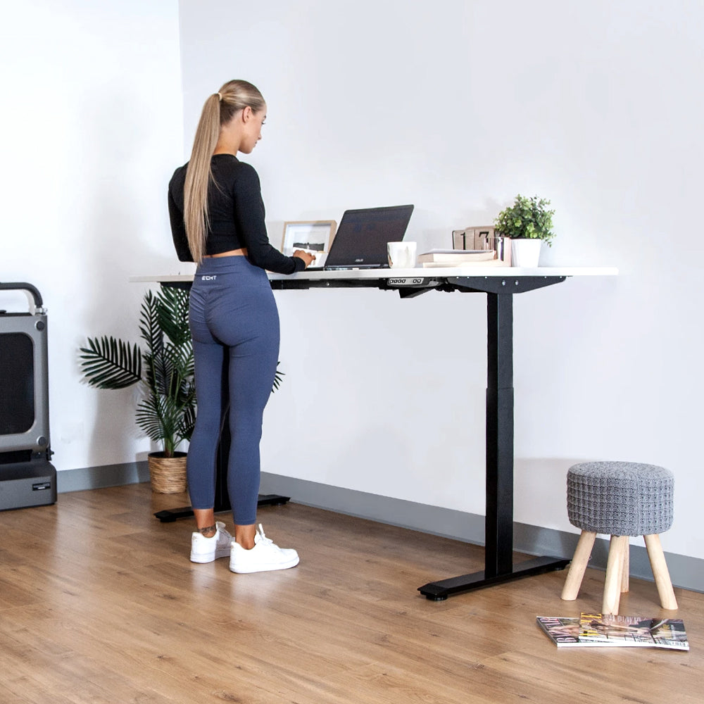 Woman working at a black standing desk raised to standing height
