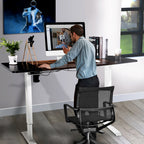 Man working at a raised standing desk with a monitor