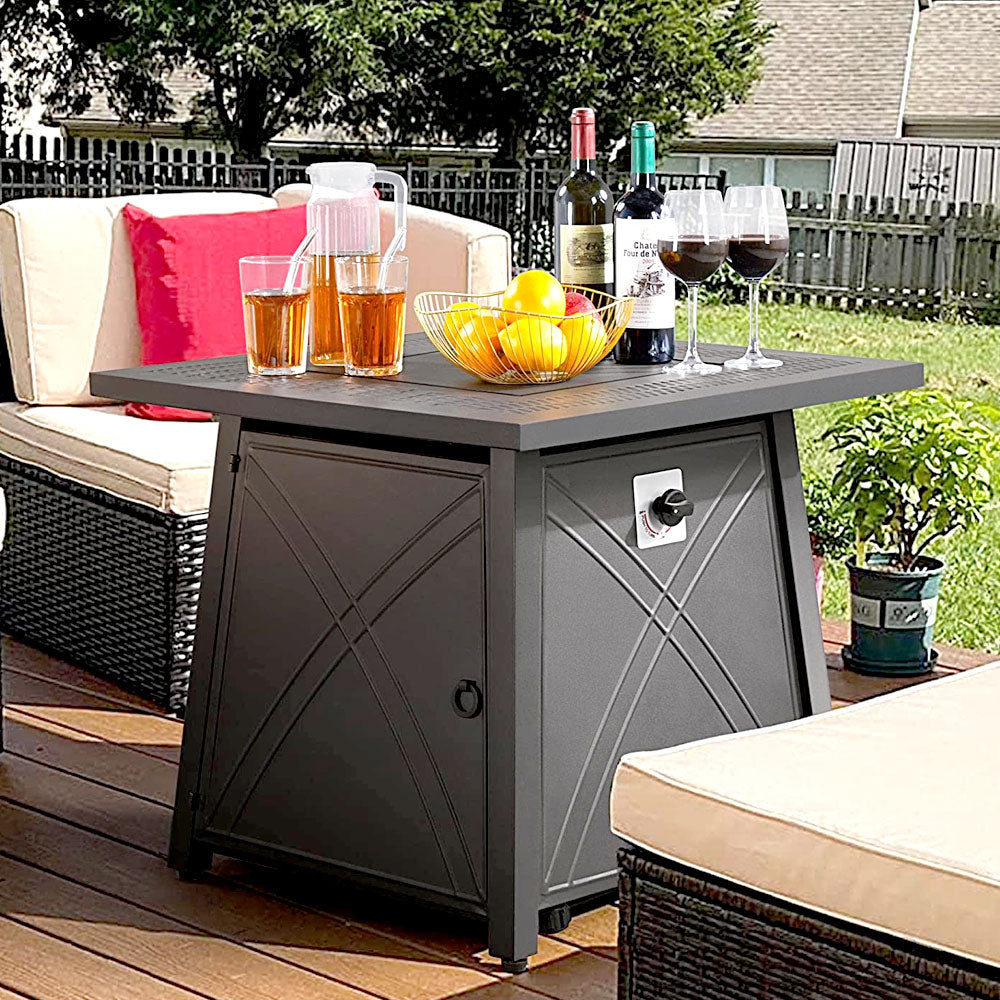 Fire pit table with drinks on a backyard patio beside wicker seating